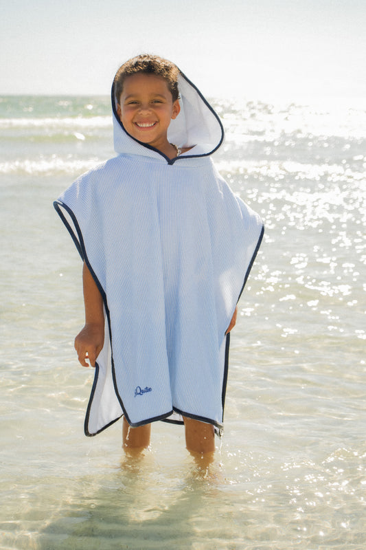 Child wearing the SRQutie Terry Towel Coverup in light blue, standing in shallow ocean water
