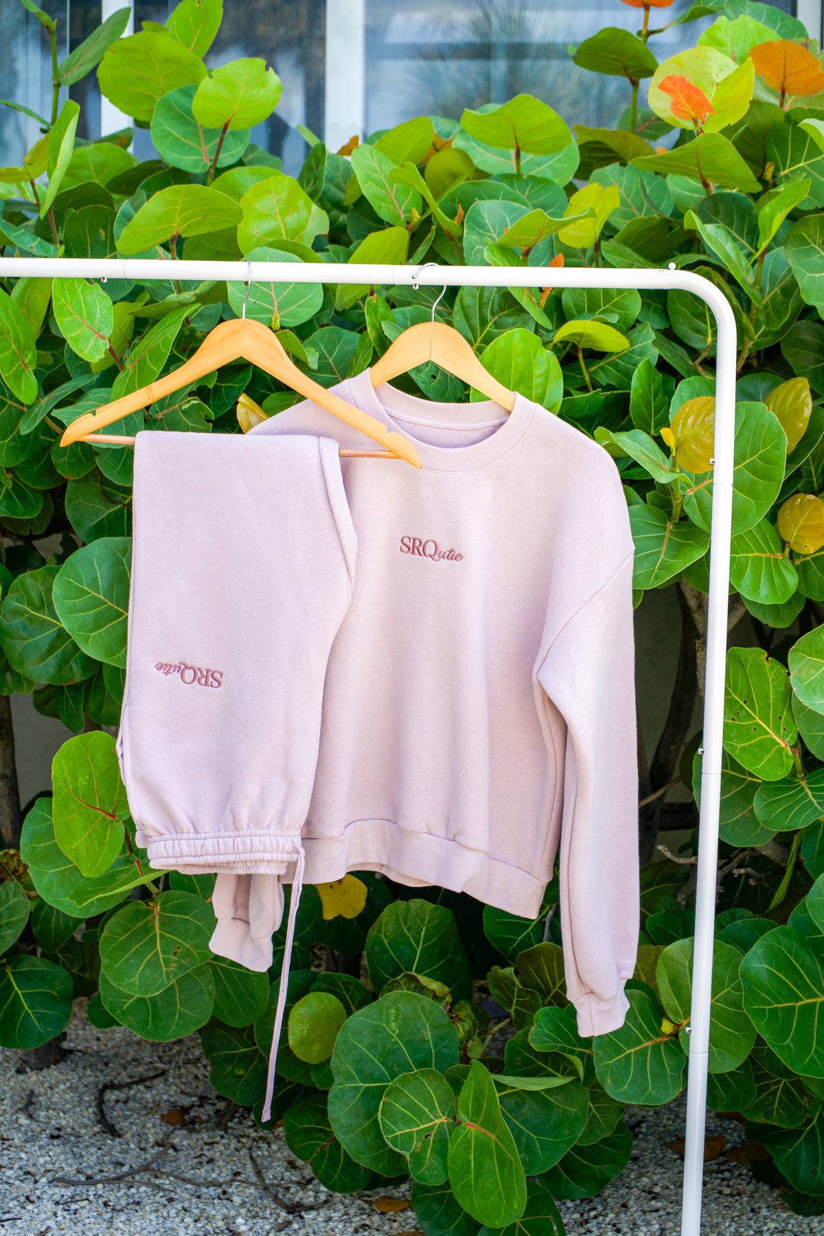 The SRQutie Logo Sweatshirt and matching Logo Sweatpants in Blush, on a hanging rack