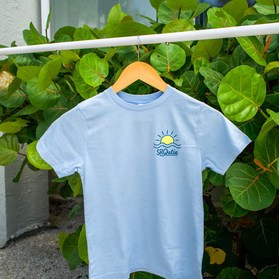 Front view of the Youth Sunset SRQutie Tee in Light Blue